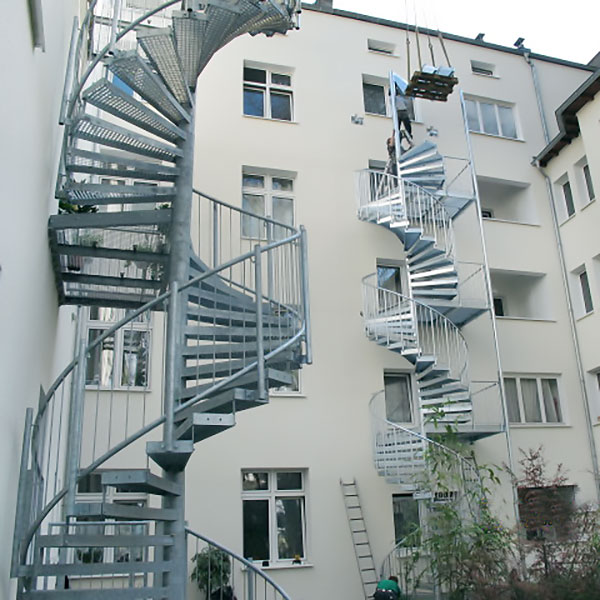 Gewendelte Fluchttreppen aus Stahl, außen vor den Fassaden eines mehrstöckigen Gebäudes
